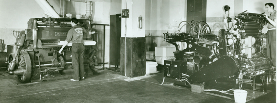 A Harris press to the right and the Seybold-Harris guillotine paper cutter to the left. Note the C&GS logo pressmen shirt on the man on the guillotine.